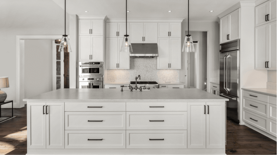 A modern white kitchen featuring a central island and sleek stainless steel appliances.