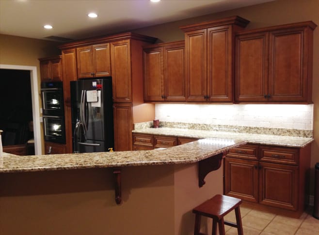 A modern kitchen featuring a stainless steel refrigerator and a sleek stove, with cabinets and countertops visible.